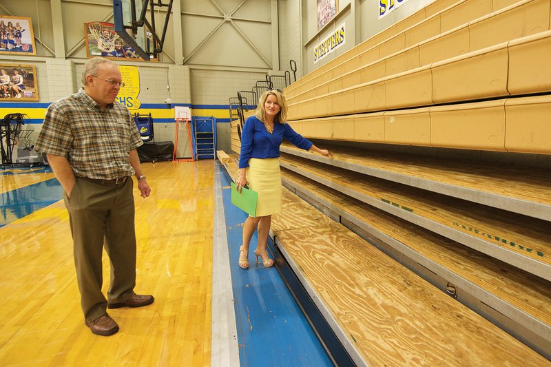 Lauren Goins, communications director for the Sheridan School District, and Rodney Williams, Sheridan High School principal, point out problems in the high school gymnasium. Parts of the bleachers in the student section are not suitable for seating; therefore, students have to stand while attending activities in the gym. Plans call for building a new multipurpose arena to replace the aging gymnasium, which would become a practice and physical-education gym