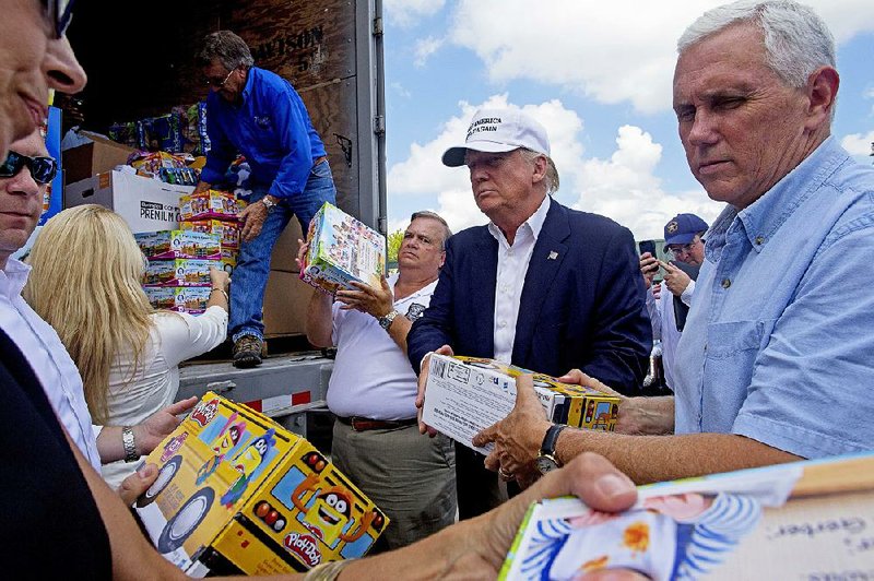 Donald Trump and his running mate, Indiana Gov. Mike Pence, (right) help unload supplies for residents during a tour of flood damage Friday in Gonzales, La. 