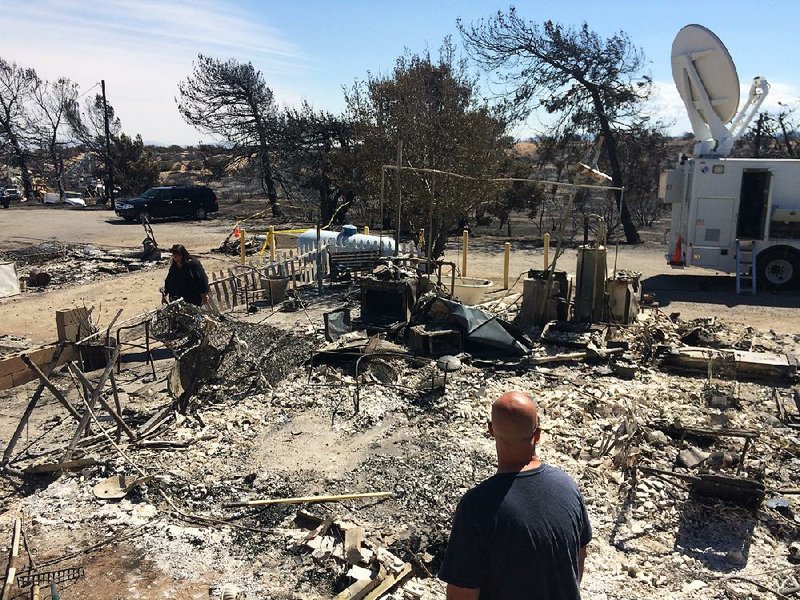Michelle and Scott Keeney search the rubble of their burned home Friday in Oak Hills, Calif. Michelle Keeney is the manager of the Summit Inn, a popular diner on historic Route 66, which sat next door to the home and burned, too. 