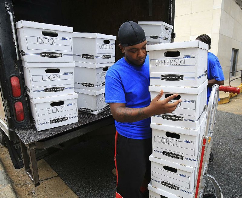 Dominic Matlock (left) and Ken Cooney of Ron’s Moving on Friday morning unload boxes of petitions on a medical-marijuana proposal to be turned over to the secretary of state’s office. 