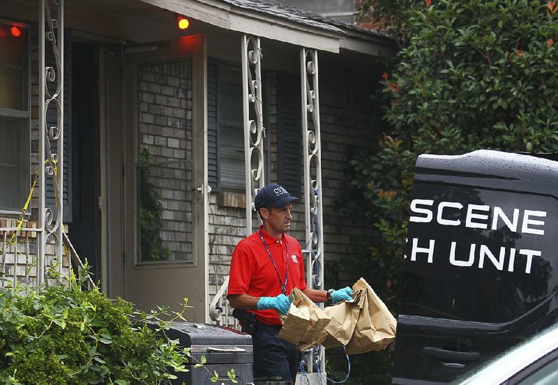 Sgt. Mike Durham of the Little Rock police’s crime-scene unit removes evidence while investigating a homicide at 10915 Mara Lynn Road on Friday morning. Police said a man was fatally shot at the home during a drug deal. 