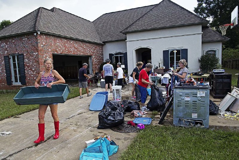 Raven Harelson, 59, carries a drawer Saturday to the trash heap in front of the home of Sheila Siener, as friends and relatives help clean out the flood-damaged home in St. Amant, La. 