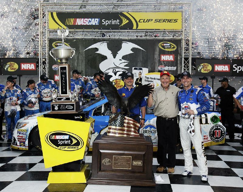 Kevin Harvick, right, celebrates after winning a NASCAR Sprint Cup Series auto race with Bass Pro Shops founder John Morris, center, and Jeff Hall, manager of Bass Pro Shops of Bristol, Sunday, Aug. 21, 2016 in Bristol, Tenn. The race was delayed Saturday night due to severe weather. 