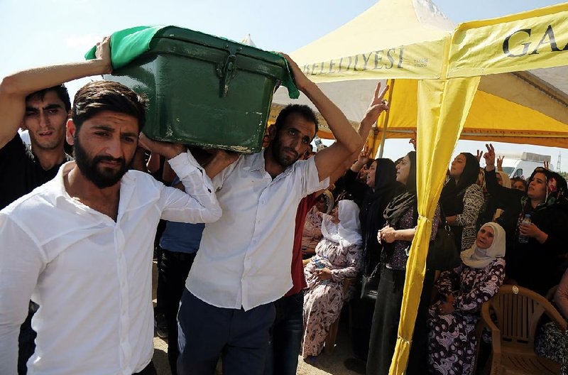 People carry a victim’s coffin during funeral services Sunday for dozens of people killed in Saturday night’s bomb attack targeting an outdoor wedding party in Gaziantep, Turkey.