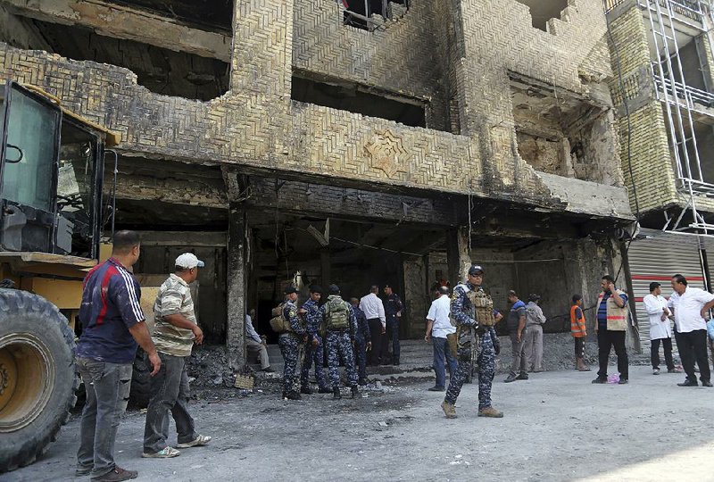 Iraqi security forces patrol Sunday as municipal workers clean up the site of a deadly mall bombing on July 3 — claimed by the Islamic State group — in the Karada neighborhood of Baghdad.