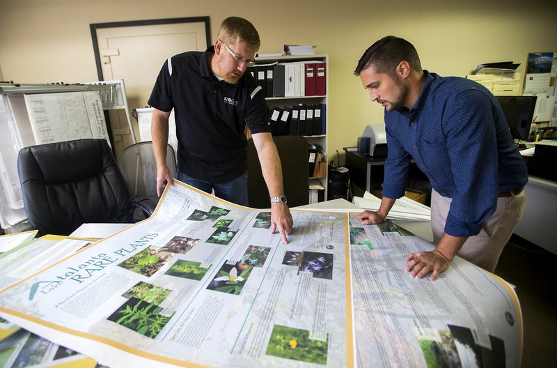 David Hook (left), facilities development manager, and Ben Cline, public relations specialist, look over mockups Friday for signs to be placed at Lake Atalanta at the Rogers City Hall.