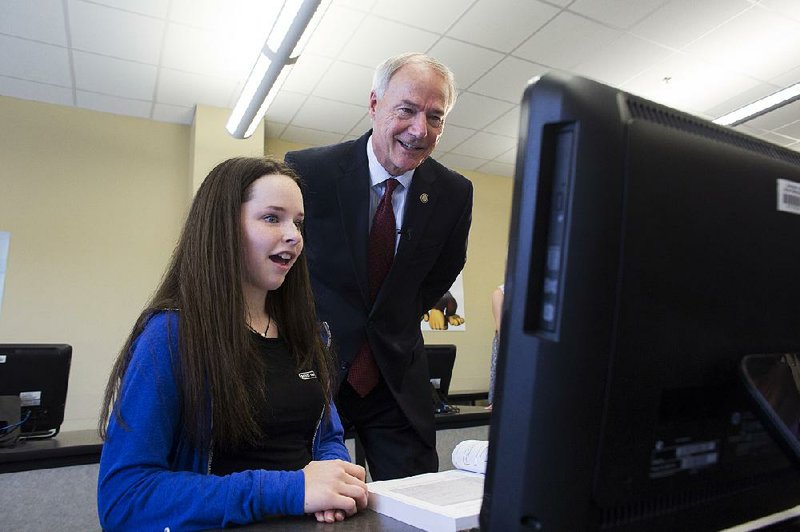Gretchen Bush, 14, explains to Gov. Asa Hutchinson an assignment she completed in Brenda Qualls’ coding class at Bryant High School on Monday. The visit, one of nine planned at high schools across the state, gave the governor an opportunity to speak to students about the benefi ts of taking computer science courses and to encourage students to sign up for coding classes this fall.