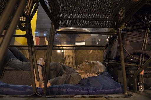 In this Aug. 10, 2016, photo, with suitcases in arms reach, homeless woman Wanda Witter beds down in her sleeping spot outside the Au Bon Pain on 13th and G Street in Washington, D.C.