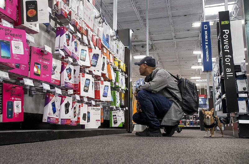 A shopper looks at prepaid cellphones displayed in a Best Buy store in San Francisco in May. The company said Tuesday that its earnings jumped 21 percent in the May to July quarter. 