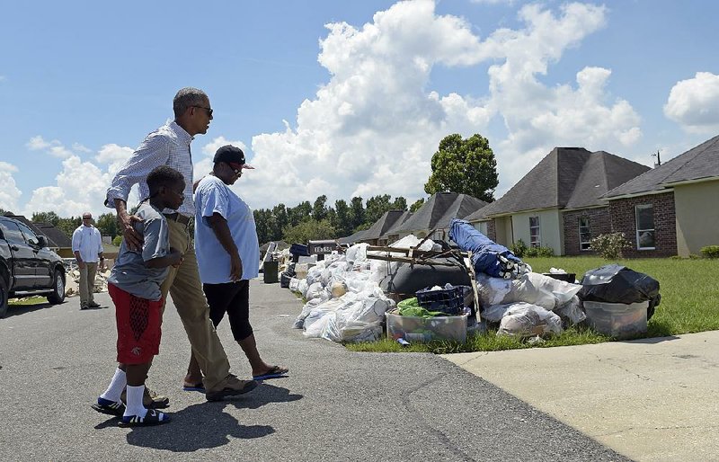 President Barack Obama accompanies members of a family to view their flood-damaged home Tuesday in the Castle Place neighborhood of Baton Rouge.