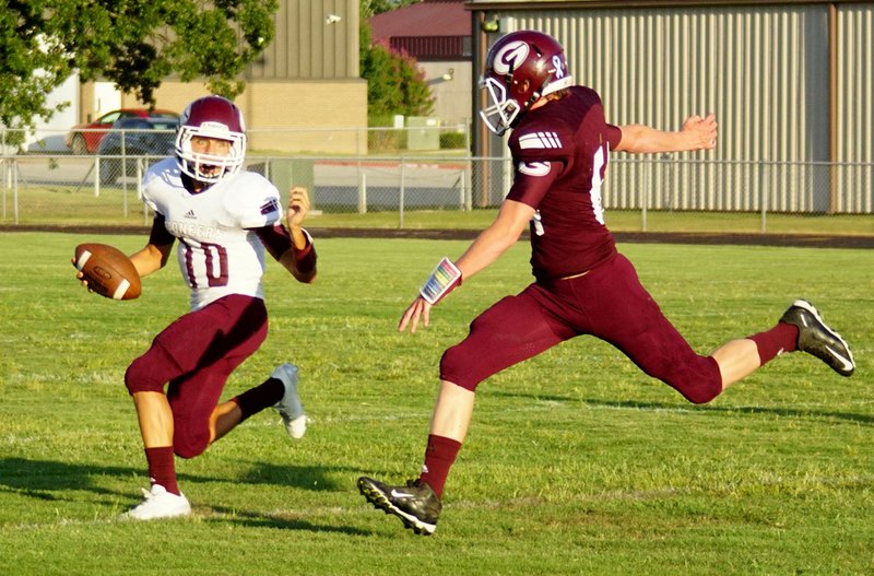 Photo by Randy Moll Garrett Matthews looks for a receiver downfield while Austin Brigance closes in during a short scrimmage held at the Meet the Pioneers event at Gentry High School on Friday night.