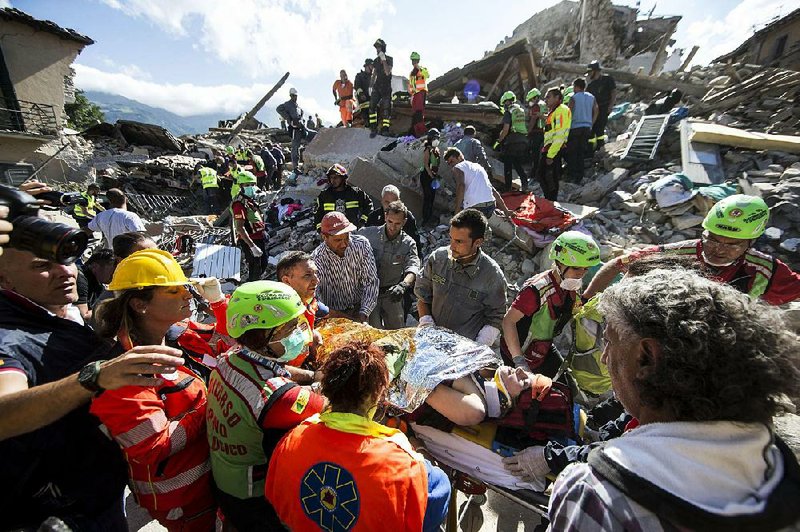 Rescuers carry an injured womanthrough the rubble Wednesday in the center of the medieval town of Amatrice in central Italy after it was hit by a strong earthquake well before dawn. Dozens of people were pulled out alive in Amatrice and nearby Accumoli by rescue teams and volunteers who arrived from across the country.