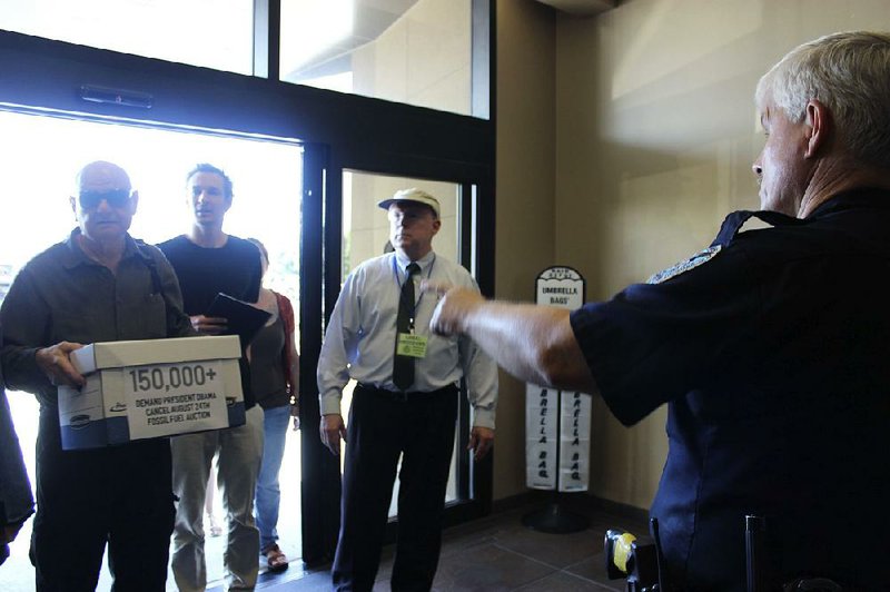 A Jefferson Parish sheriff’s deputy (right), tells a protester carrying a box with a copy of a petition against federal oil lease sales that he cannot enter the offices of the Bureau of Ocean Energy Management in Harahan, La., on Tuesday. 