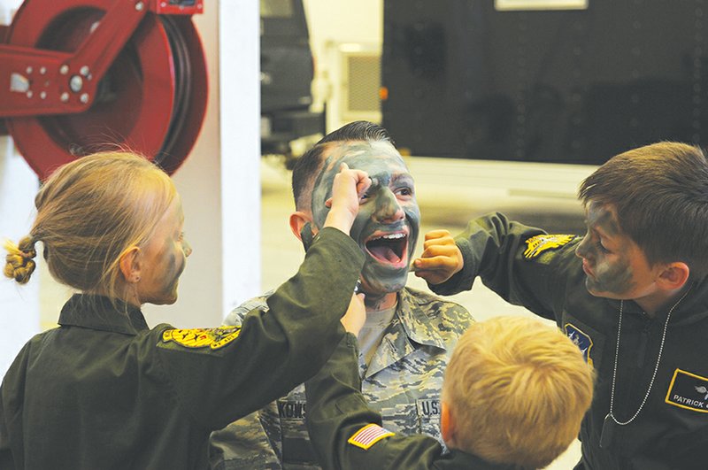U.S. Air Force Airman First Class Randy Oczkowski, 19th Operation Support Squadron Air Traffic Controller, center, has his face painted by siblings Lily, from left, Henry and Patrick Griego during a camouflage face painting activity in a hangar April 9 at Little Rock Air Force Base. Such children’s activities will be available at the 2016 Arkansas Military Expo, which takes place at the base Sept. 17.