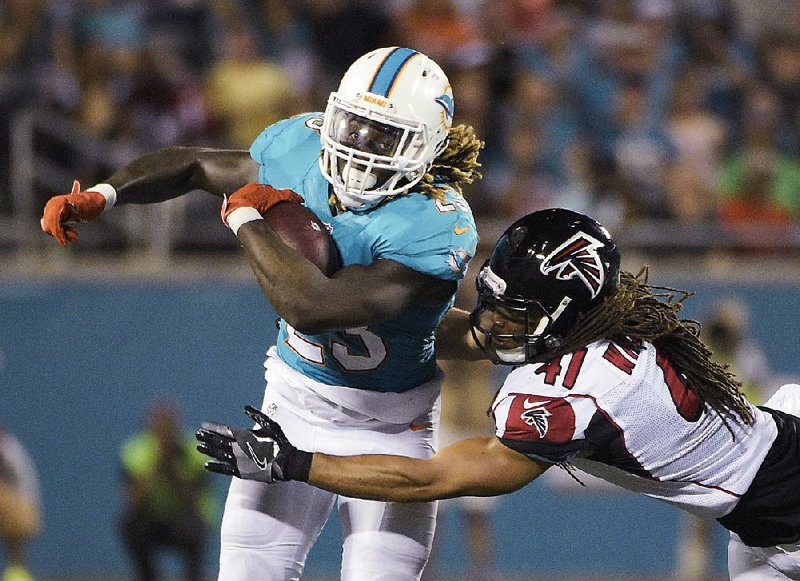 Miami Dolphins running back Jay Ajayi tries to get away from Atlanta Falcons linebacker Philip Wheeler during Thursday night’s NFL exhibition game.