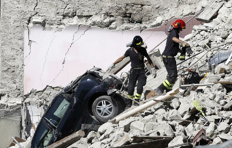 Rescuers climb through an earthquake-devastated house Thursday in Pescara Del Tronto in central Italy. A rescue team spokesman vowed to “work relentlessly until the last person is found.” 