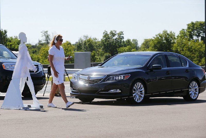 A pedestrian passes in front of a vehicle in this file photo taken during a demonstration at the University of Michigan in Ann Arbor, Mich.