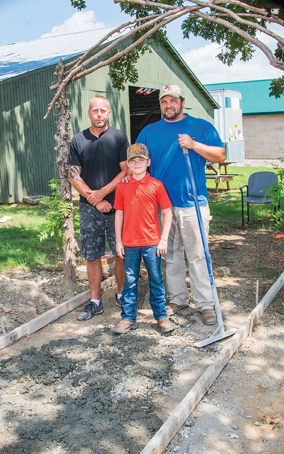Gregory Erickson, left, owner of American Landscapes; Riley Wayne Pate, 9, and his father Thomas Pate, owner of TPA MetalWorks, Concrete and Excavating, pose at the archway of the killed-in-action walkway Pate is building at the Museum of Veterans and Military History in Vilonia. Fundraisers, including a talent show on Sept. 10, are scheduled to go toward the walkway, as well as a multipurpose pavilion/chapel that will be available for free for veterans’ memorial services and a Gold Star Families Garden.