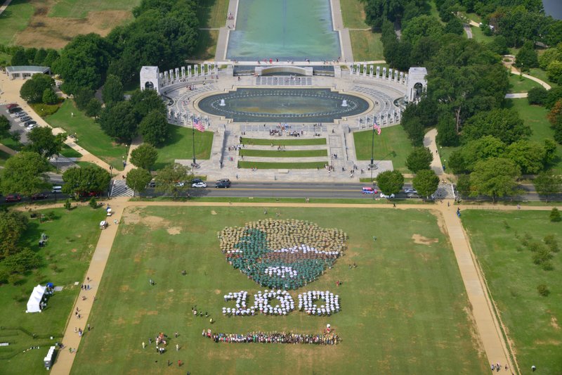 This photo provided by the National Park Service shows people on the National Mall in Washington, looking toward the World War II Memorial, Thursday, Aug. 25, 2016, creating a giant, living version of the National Park Service emblem. Participants used brown, green and white umbrellas to create the emblem. 
