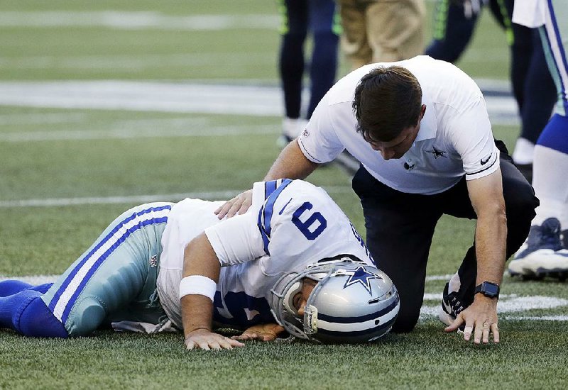 Dallas Cowboys quarterback Tony Romo is tended to by a team trainer after going down with a back injury during Thursday night’s exhibition game against the Seattle Seahawks.