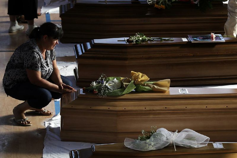 A woman mourns Friday at one of the coffins of earthquake victims lined up in a gymnasium in the Italian city of Ascoli Piceno. Rescuers acknowledged that they might not find any more survivors in the rubble of hard-hit Amatrice, which was shaken Friday by a strong aftershock. 