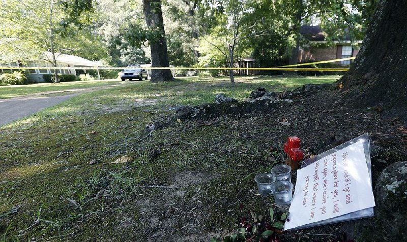 A piece of Scripture, a cross, three candles and some faded flowers serve as a memorial near the Durant, Miss., home where two nuns were found slain. 