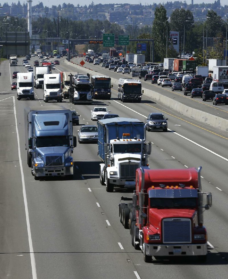 Tractor-trailers roll with the traffic on Interstate 5 near Fife, Wash. The American Trucking Associations backs a proposal to limit the speed of heavy-duty vehicles. 