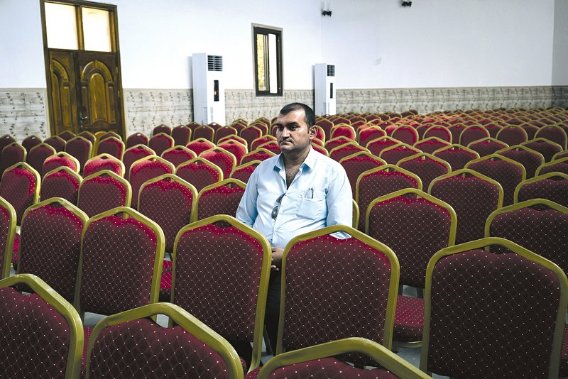 Rami Hannah Qaroumi, an Iraqi Christian from Qaraqosh, sits in the Assyrian church where he works in Irbil, Iraq. He fled to France with his family, but after a few months decided to return to Iraq. He is now once again considering going back to Europe. 