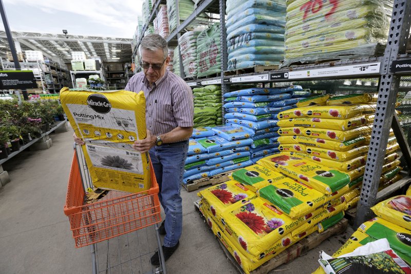 In this Wednesday, May 18, 2016, photo, Joe Russo, of Medway, Mass., puts a bag of potting soil into a cart while shopping at a Home Depot store location, in Bellingham, Mass. 