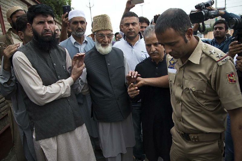 An Indian officer (right) detains Syed Ali Shah Geelani (center), a separatist leader in India-controlled Kashmir, after Geelani tried to participate in a march Saturday toward an army base in Srinagar. Mirwaiz Umar Farooq, a key figure in regional protests, was arrested Friday night, police said.