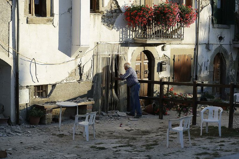A man in the village of Santi Lorenzo e Flaviano, Italy, removes his belongings Saturday after an earthquake damaged his house last week.