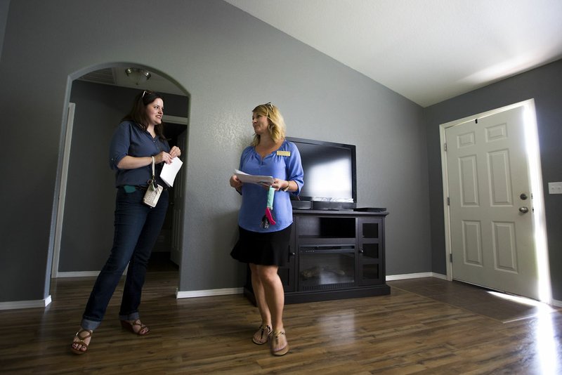 Abby Williams (left), 24, talks with Melony Belt, real estate agent with Lindsey & Associates in Fayetteville, on Tuesday at a home for sale in the Summerlin subdivision in Bentonville.