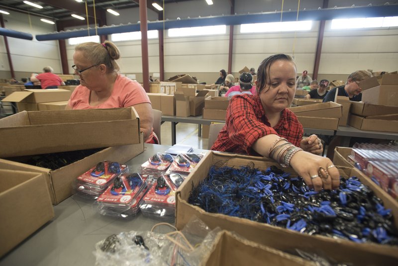 Karen Vradenburg (left) and Brianna Benham, both of Rogers, assemble fishing lures at Open Avenues, a nonprofit organization in Rogers which assists adults with disabilities in learning job skills.