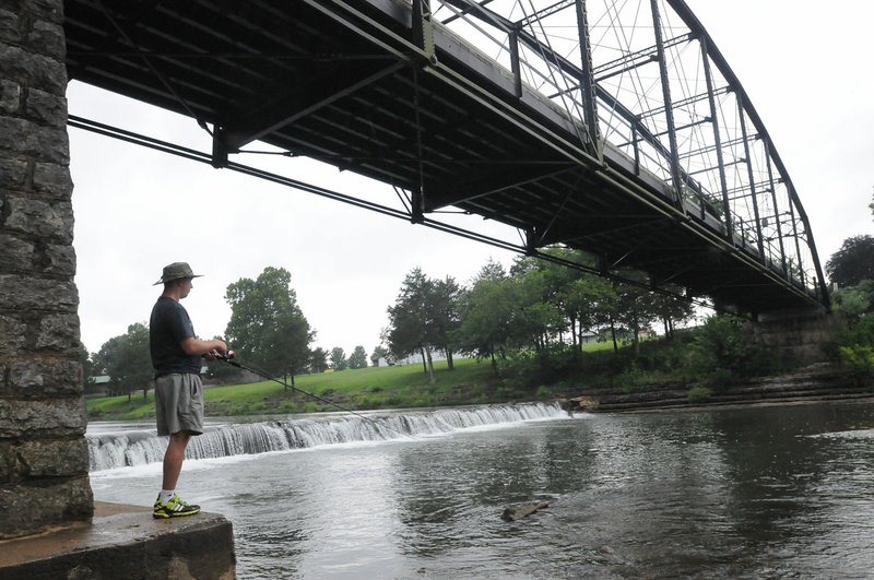 Nick Hamilton of North Little Rock fishes July 6 below the historic War Eagle Bridge. Benton County officials are optimistic repairs to the bridge can begin around Nov. 1 and be completed before the 2017 spring craft fair in May.