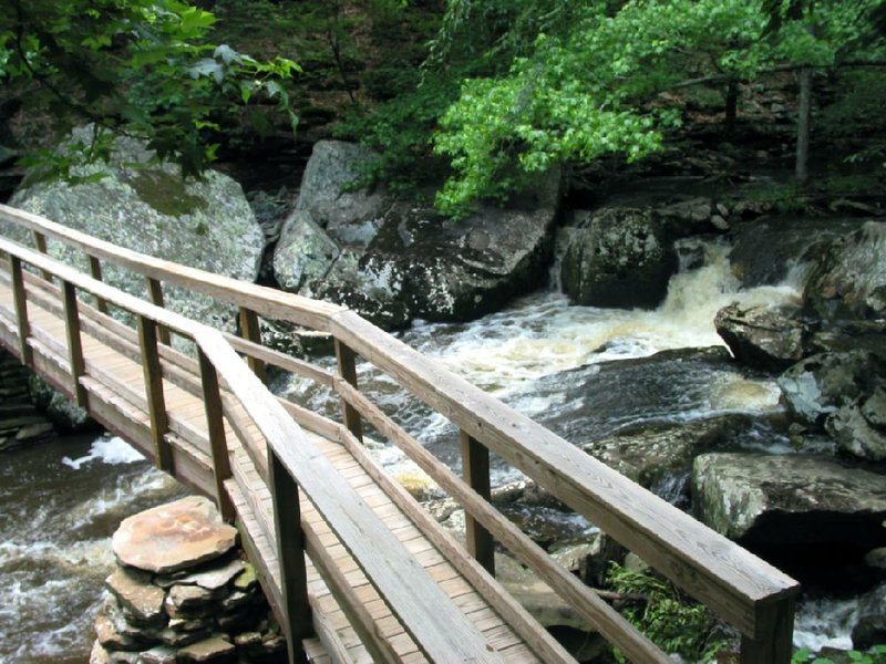 Cedar Creek cascades beneath a wooden bridge along Cedar Creek Trail at Petit Jean State Park.



