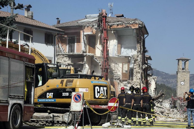 Firefighters stand by an excavator in the quake-hit town of Amatrice, Italy, on Sunday.