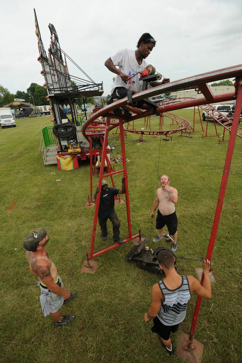 Charles Wiley (clockwise from top) works Friday with Nick Forrier, Ian Girior and Andrew Rohloff, as they assemble the Orient Express ride while preparing for the Washington County Fair in Fayetteville.