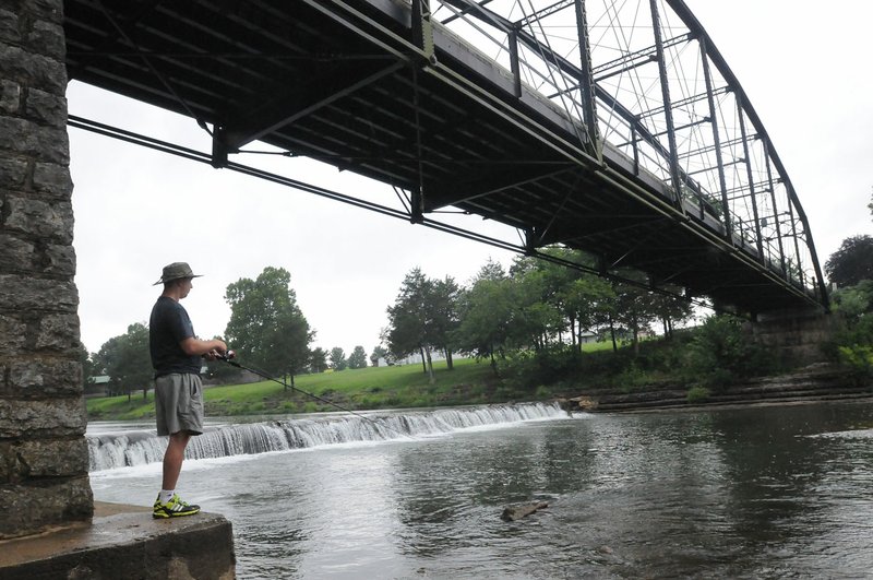 Nick Hamilton of North Little Rock fishes Wednesday July 6, 2016 below the historic War Eagle Bridge. Hamilton said he's in the area on vacation. He fished in the War Eagle River before heading to Hobbs State Park-Conservation Area to ride his mountain bike.