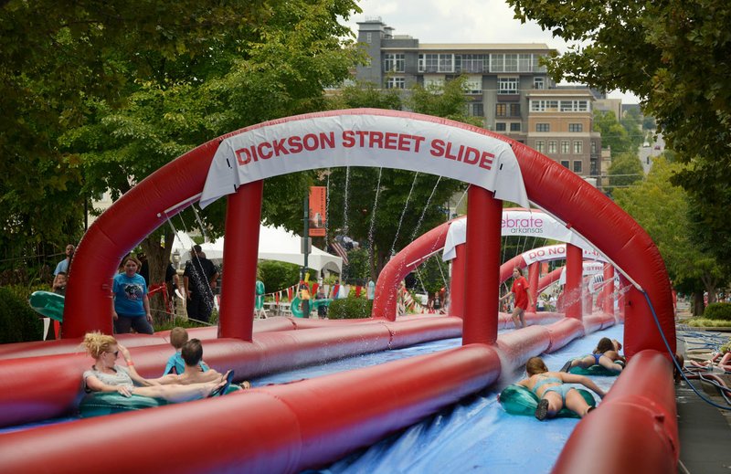 Patrons slip and slide their way down Dickson Street Sunday during the Dickson Street Slide event in downtown Fayetteville.