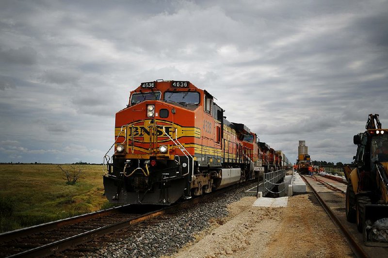 A Burlington Northern Santa Fe freight train passes maintenance workers in Alva., Okla., in this fi le photo. The railroad is working with the FAA to develop procedures for operating drones beyond a pilot’s line of sight. The drones will be used to inspect BNSF’s 32,500 miles of track. 