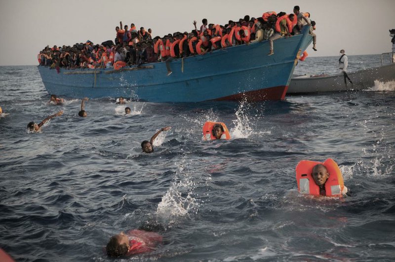 Migrants, most of them from Eritrea, jump into the water from a crowded wooden boat during a rescue operation Monday in the Mediterranean Sea off the Libyan coast. 