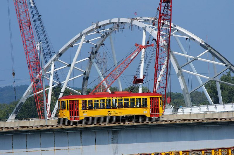 The River Rail trolley crosses the Main Street Bridge into North Little Rock on Tuesday beside the arches of the new Broadway Bridge.