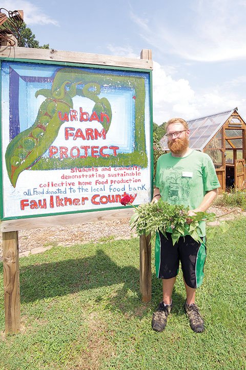 Sean Ott stands by the Faulkner County Urban Farm Project sign in the garden north of the Faulkner County Library, 1900 Tyler St. in Conway. Ott is the library’s first garden programmer. He will work with the third and final Arkansas GardenCorps service member this year, who oversees the garden, the Garden Club and a book club.