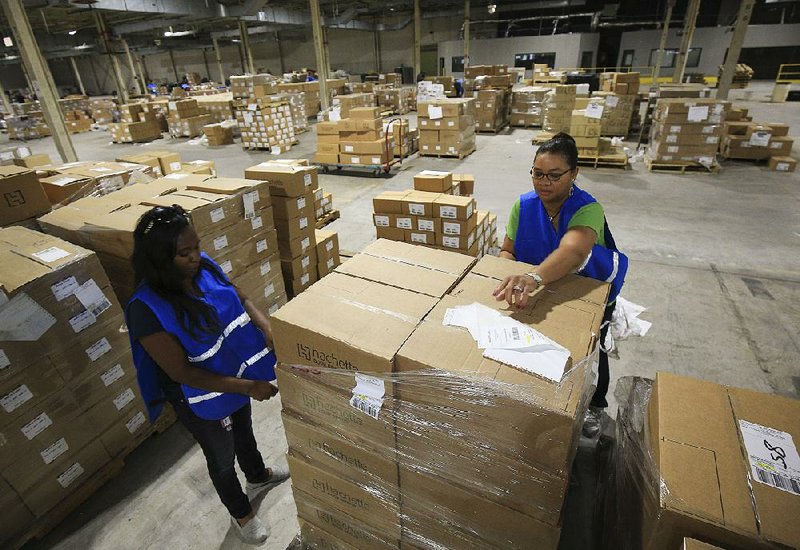 Volunteers Chakina Phillips-Parker (left) and Sharon Frazier load up a cart Wednesday afternoon at Goodwill Industries of Arkansas in Little Rock as they sorted more than 100,000 books to be distributed to needy children across the state.