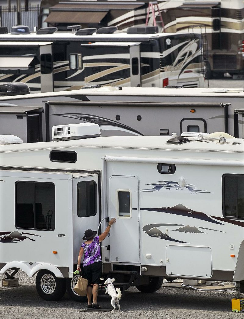 A traveler takes her dog for a walk while parked at the North Little Rock RV Park, where a full lot is expected this weekend for the Labor Day holiday. 