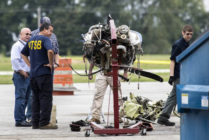 John Brannen (foreground), senior air safety investigator with the National Transportation Safety Board, and other officials view the remains of an engine Thursday, a day after a plane crash at the Bentonville Municipal Airport. 