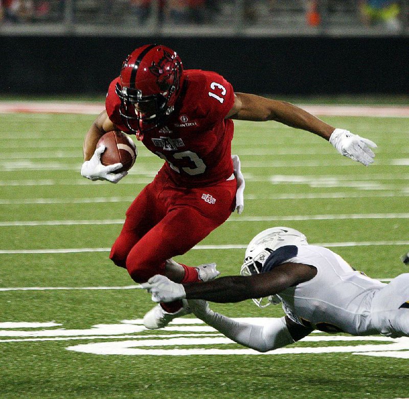 Arkansas State running back Christian Booker is tripped up by a Toledo defender during Friday night’s game in Jonesboro. Toledo held ASU to 266 yards of offense in cruising to a 31-10 victory.