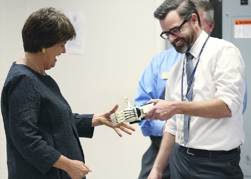 Anne Holton, wife of Democratic vice presidential candidate Tim Kaine, tries shaking hands Friday with a 3-D-printed prosthetic hand made by Virginia Western student Jason Garnett during a tour of a lab at the community college in Roanoke, Va., while campaigning.