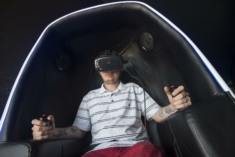Dustin McVay of Seligman, Mo., rides a virtual roller coaster at Virtual Game World & Event Center in Rogers. The virtual reality industry is expected to grow from $90 million in 2014 to $5.2 billion in 2018.