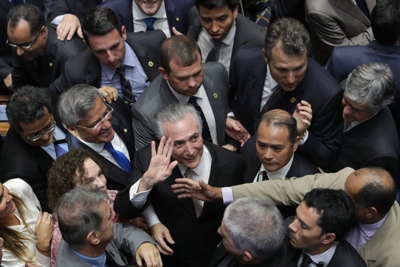 In this Wednesday, Aug. 31, 2016 photo, Brazil's President Michel Temer, center, is surrounded by senators as he arrives to take the presidential oath at the National Congress, in Brasilia, Brazil.